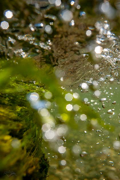 Wasseroberfläche und glänzende Luftblasen im strömenden Fluss